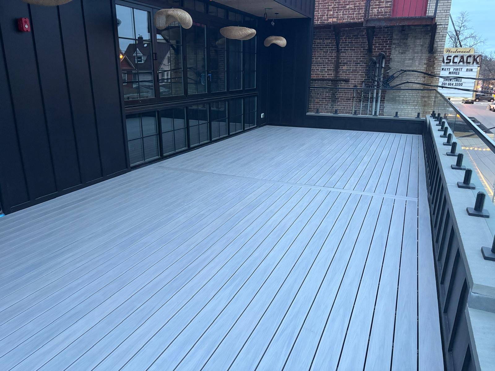 Completed rooftop terrace with glass railing and pendant lighting