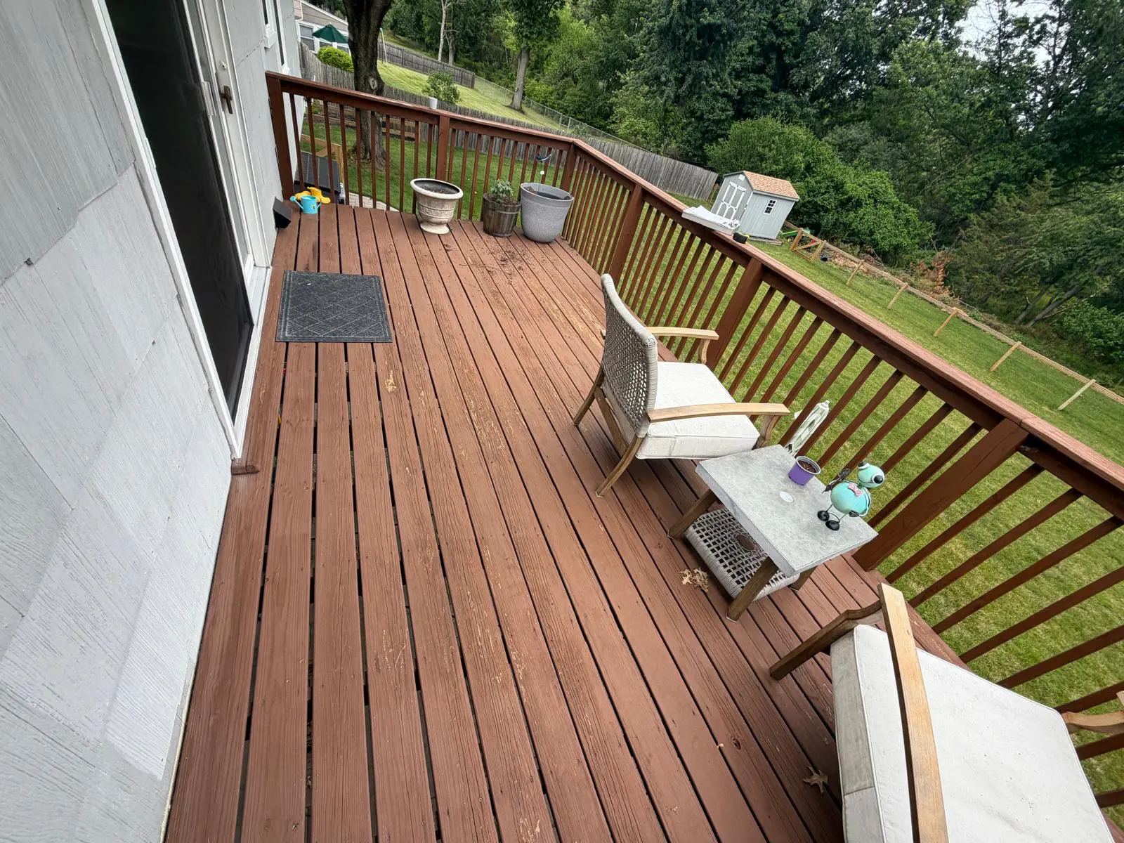 Weathered red-brown deck with faded boards and timber railings before refinishing