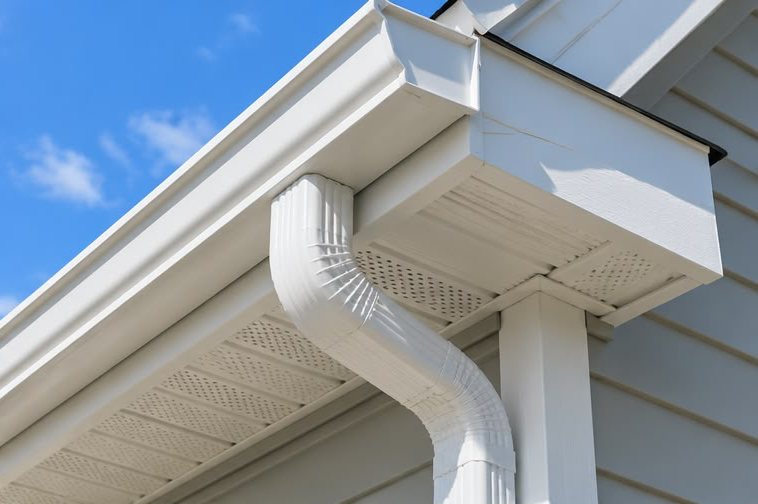 White gutter and curved downspout elbow under a white soffit