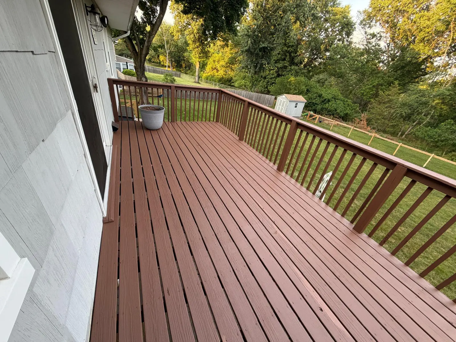 The same deck after refinishing, with a fresh, even brown surface and clean railings