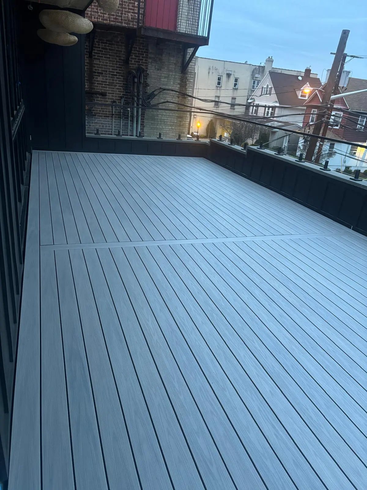 Finished rooftop deck with grey composite boards and glass railing