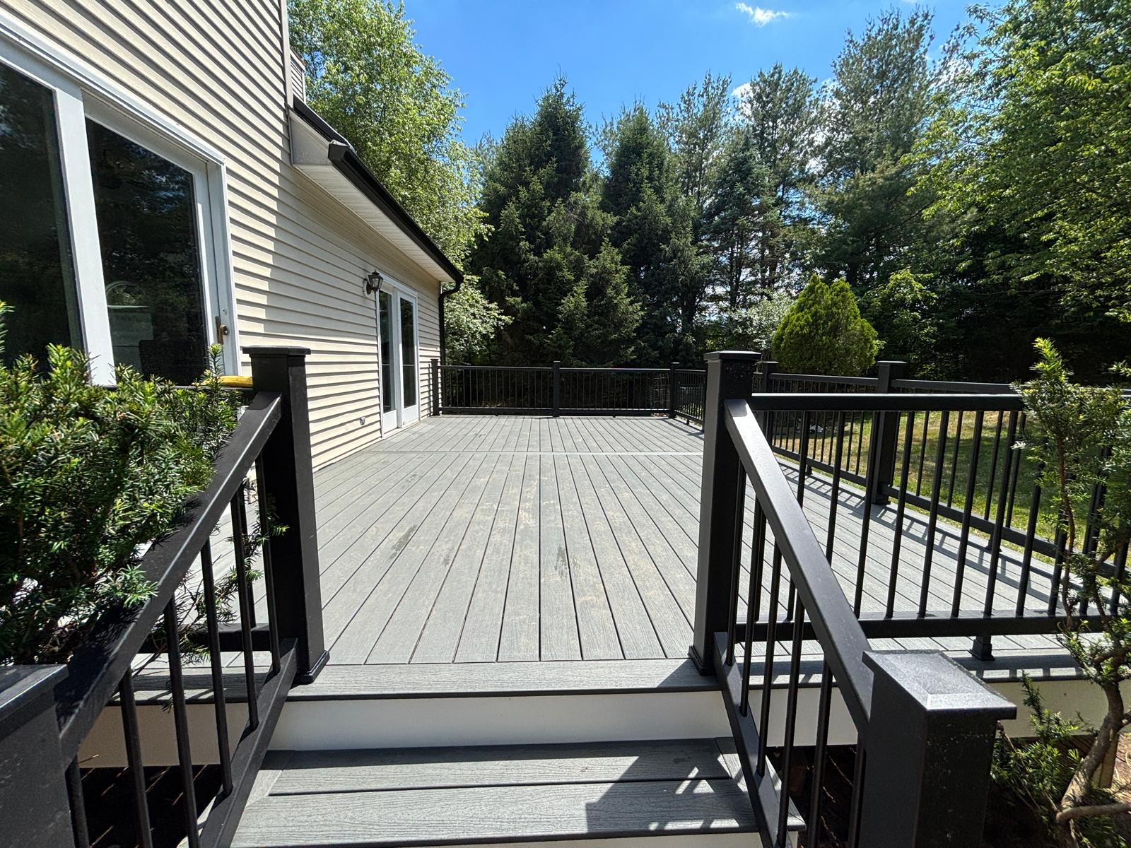 Completed deck with grey decking and black railings on a real New Jersey residential project