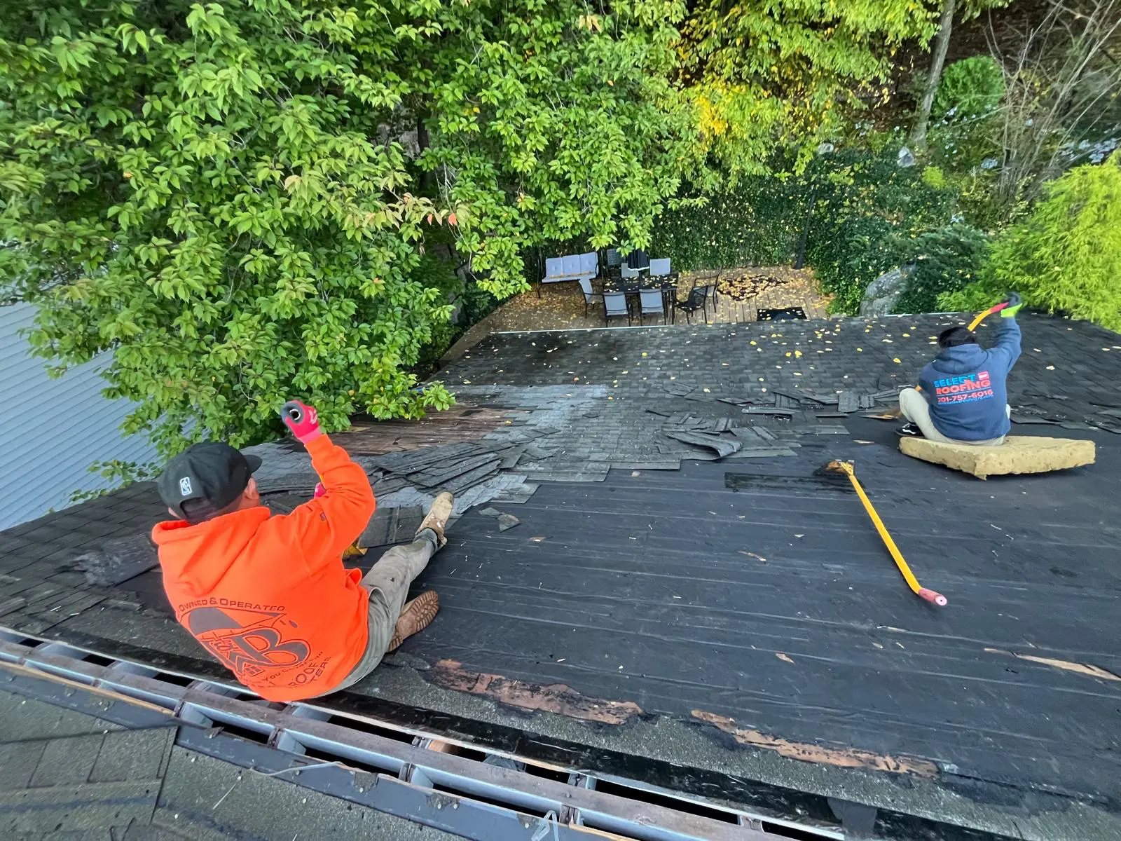 Crew removing old shingles from the roof during tear-off