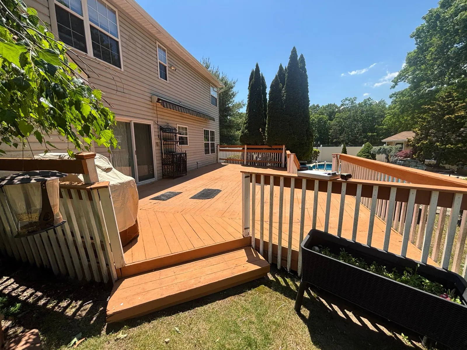 Weathered orange-stained deck with worn white railings before the rebuild