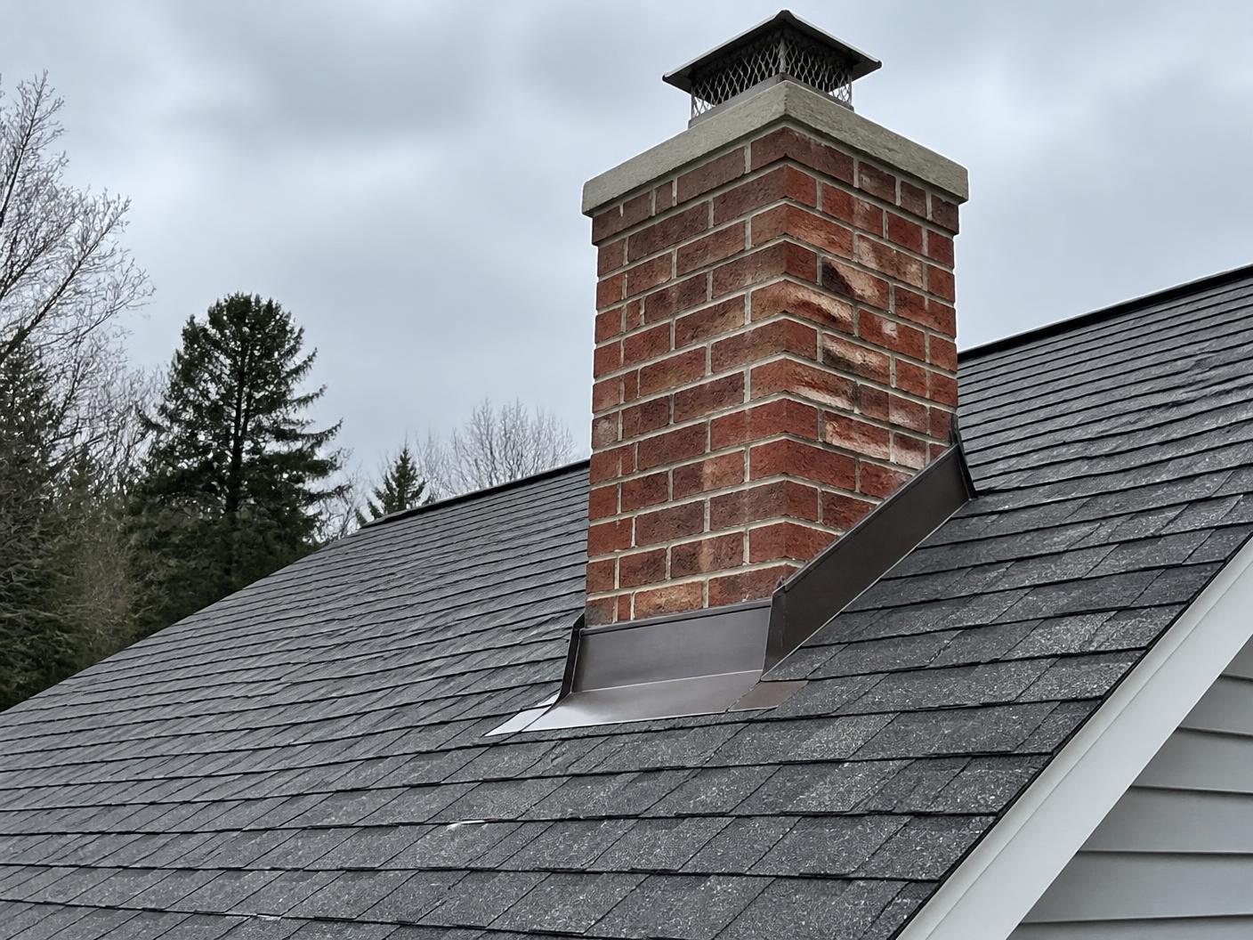 Chimney with new metal flashing set into a finished shingle roof